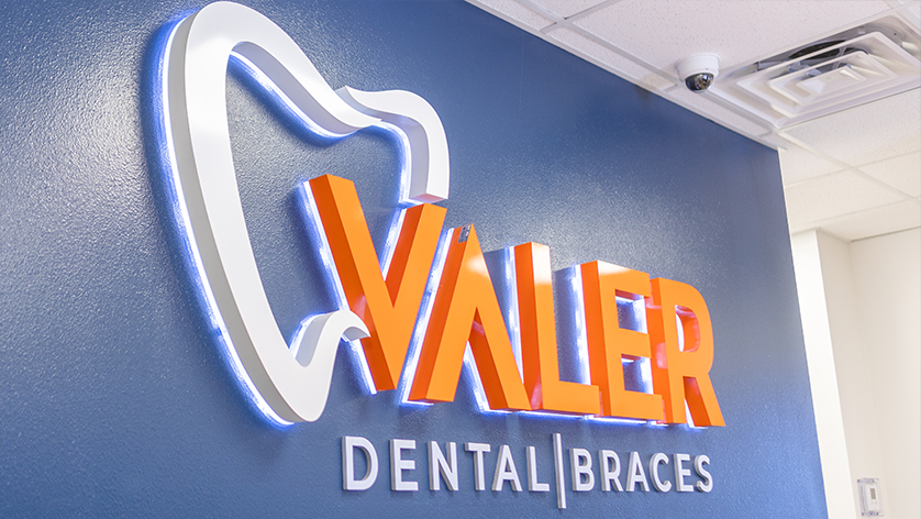 Valer Dental and Braces sign on wall behind dental office front desk