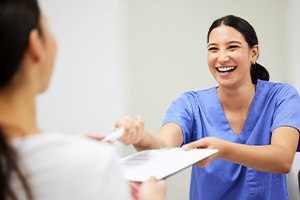 Dental assistant smiling while handing patient form