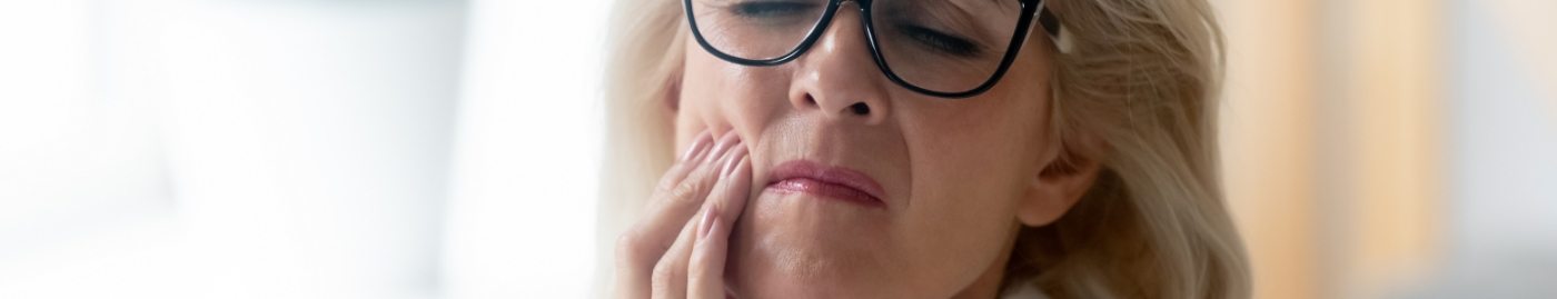 Wincing woman holding her cheek in pain needing emergency dentist in Albuquerque