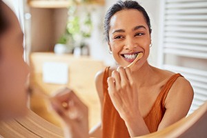 Woman smiling while brushing her teeth