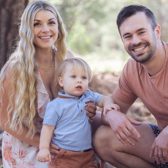 Doctor Belle smiling in first with her husband and toddler son
