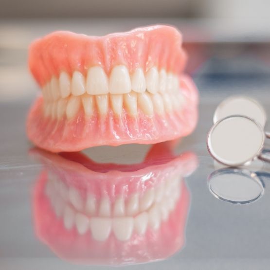 Full dentures resting on tray next to dental mirrors