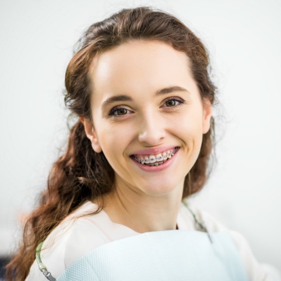 Woman in dental chair smiling with traditional braces